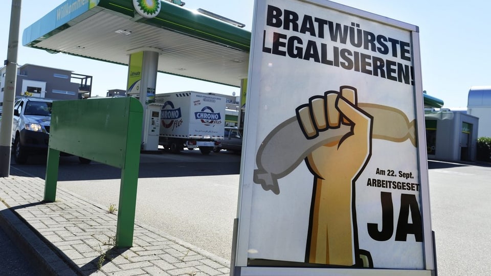 Tankstelle mit Plakat, auf dem «Bratwürste legalisieren» steht
