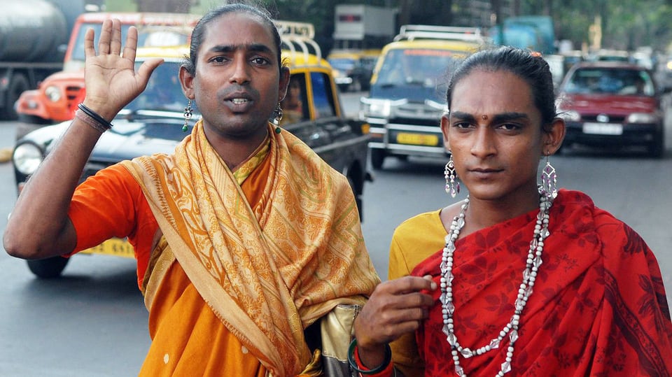 Zwei indische Männer in Frauenkleidung stehen am Strassenrand.