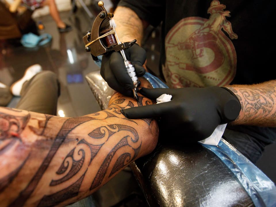 Tätowierer sticht ein Maori-Muster.