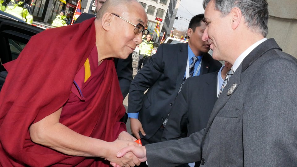 Der Dalai Lama und Guy Morin begrüssen sich mit Händedruck in Basels Strassen.