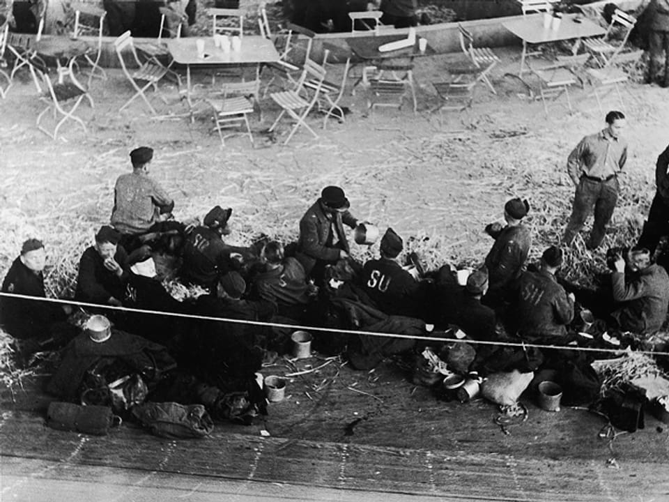 Russische Flüchtlinge auf dem Boden im Hallenstadion sitzend. Sie wurden 1945 im Hallenstadtion beherbergt.