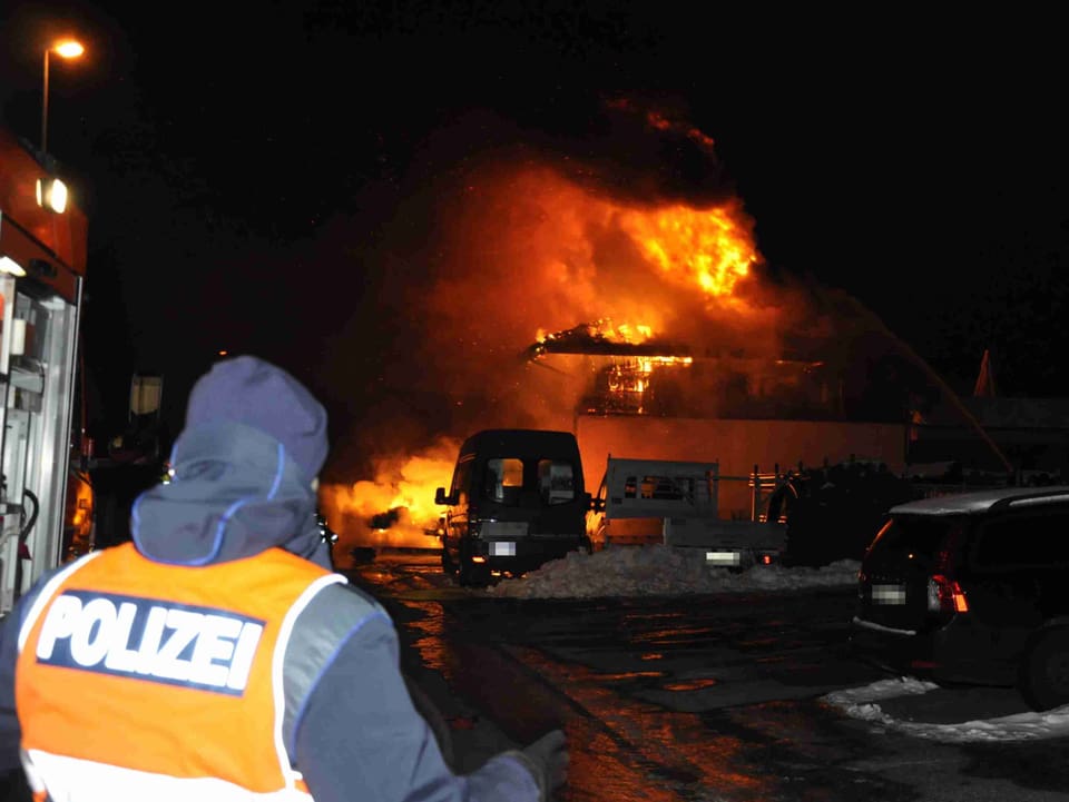 Ein Poliziste vor einem brennenden Haus