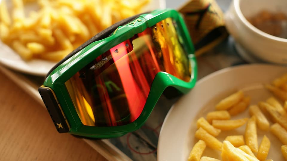 Eine Skibrille zwischen zwei Tellern Pommes Frites