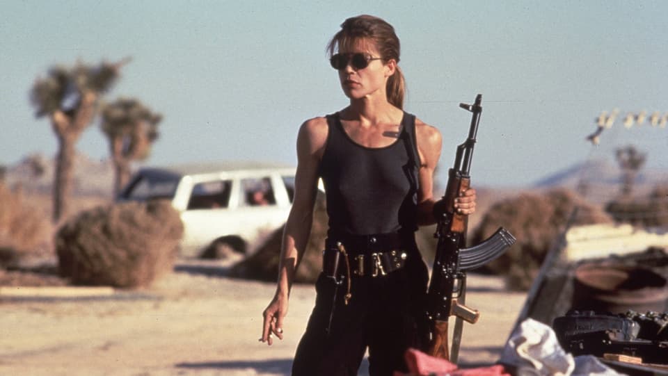 Eine junge bewaffnete Frau mit Sonnenbrille.