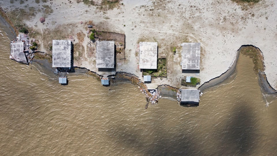 Luftaufnahme von Häusern, die an einer Küste stehen und gefährlich nahe am Wasser stehen. 