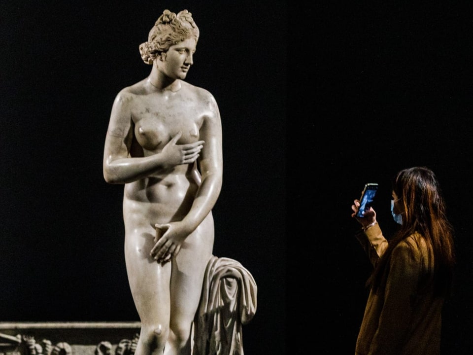 Eine Frau schaut eine antike Statue einer nackten Frau an