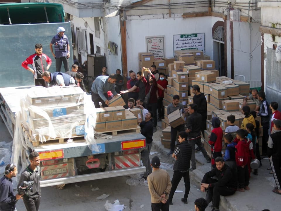 Menschen laden Hilfsgüter von Lastwagen ab.
