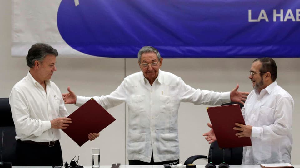 Kolumbiens Präsident Juan Manuel Santos und Rodrigo Londoño reichen sich die Hände. Dahinter Raul Castro