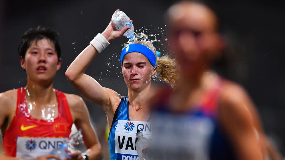 Eine Marathonläuferin leert sich Wasser über den Kopf.