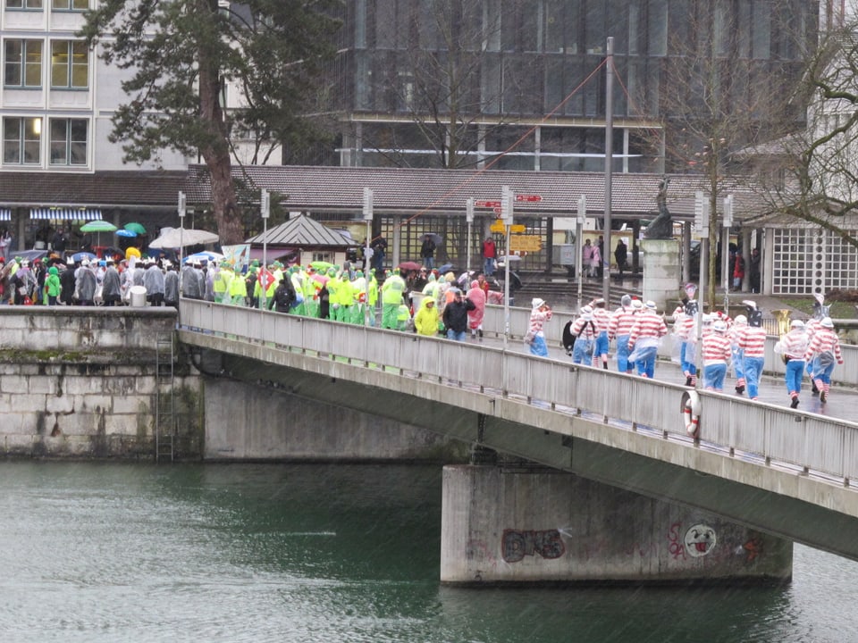 Farbig verkleidete Truppen eilen über die Brücke. 