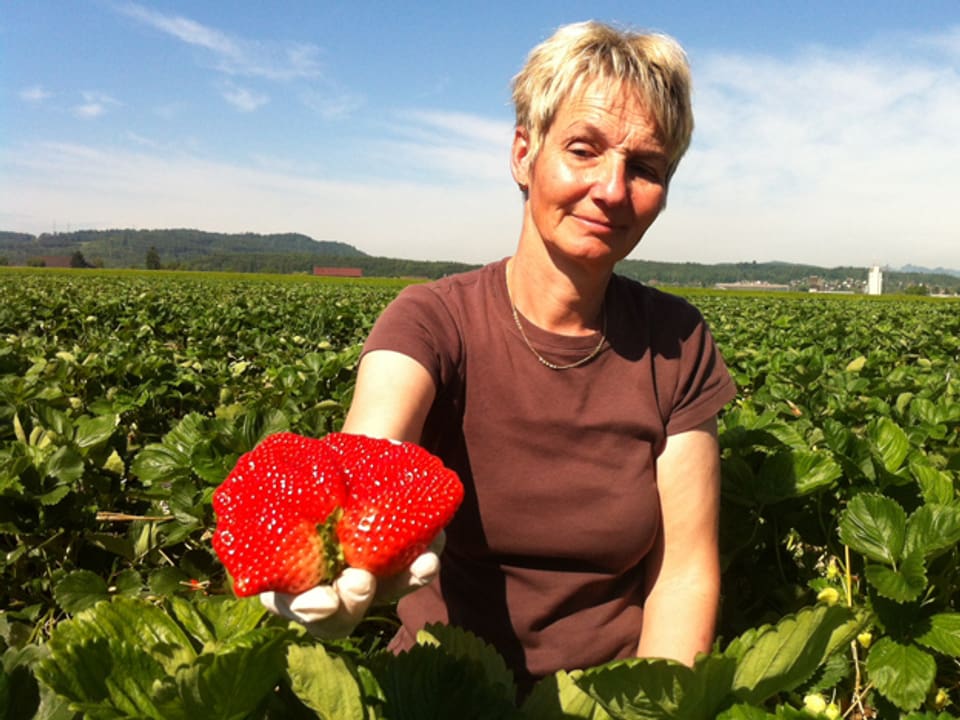 Vreni Knüsel mit grosser Erdbeere im Feld.