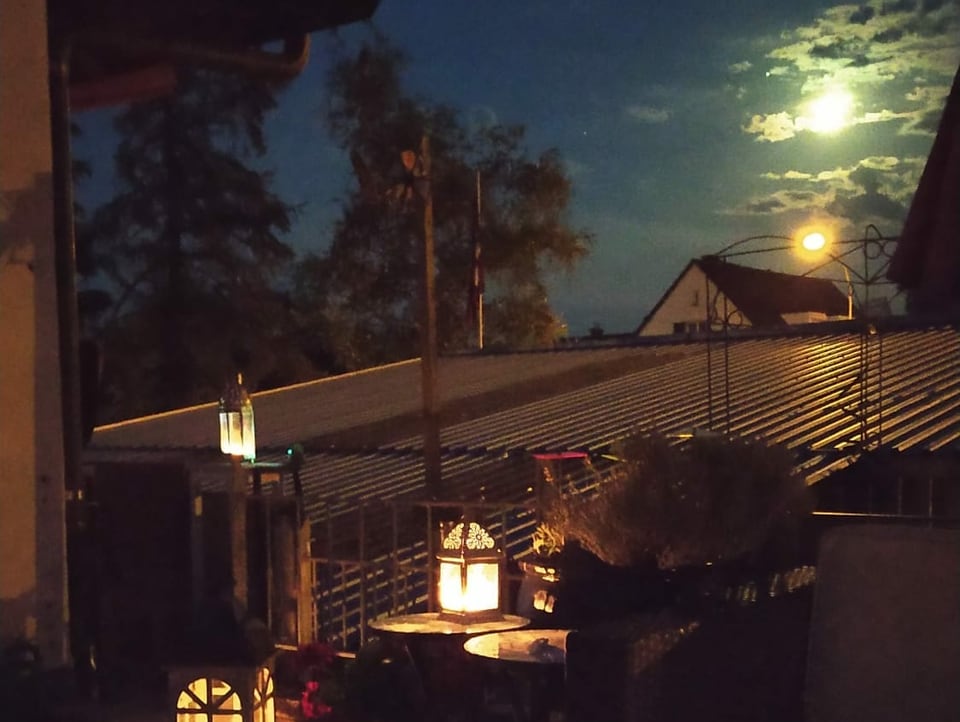 Der Mond strahlt über den Dächern. 