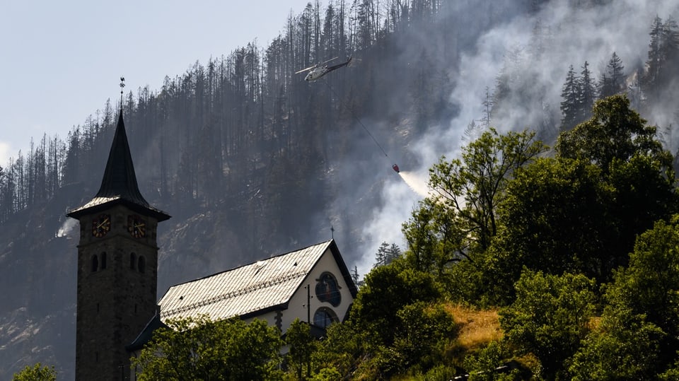 Ein Helikopter der Air Zermatt löscht die Brände im Wald