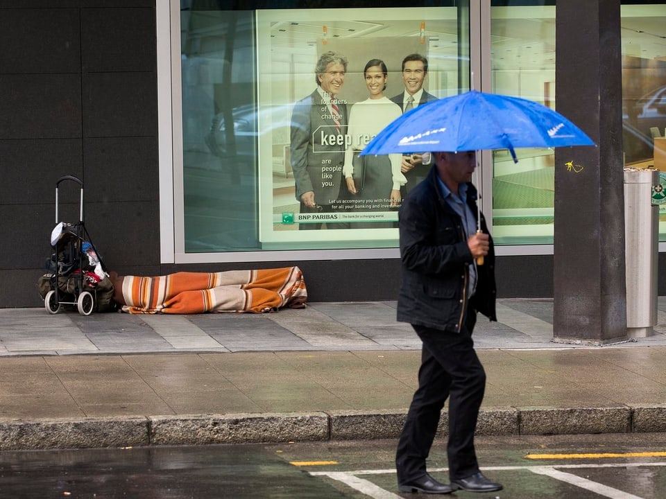 Ein Obdachloser liegt in Genf auf dem Trottoir.