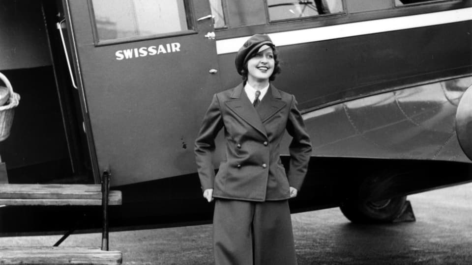Schwarzweissaufnahme, Frau in Uniform lächelt vor Flugzeug