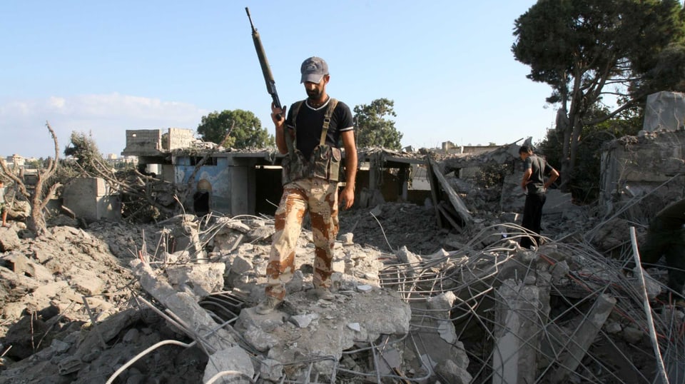 Kämpfer inspiziert Überreste eines zerstörten Gebäude im Flüchtlingslager, 2006.
