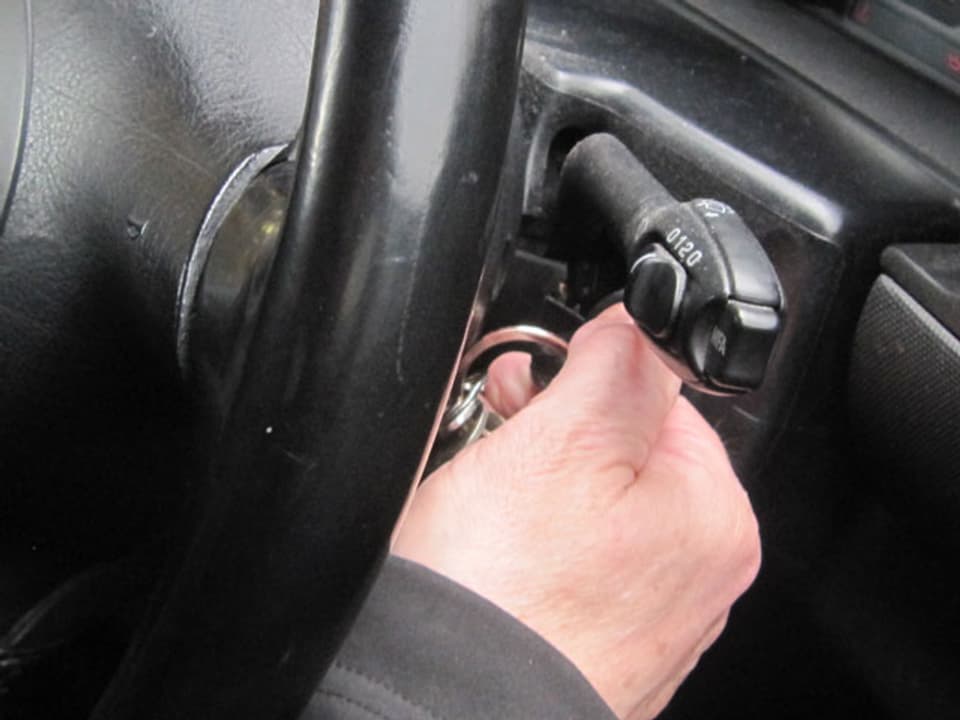 Nahaufnahme einer Hand, die einen Zündschlüssel im Auto dreht.