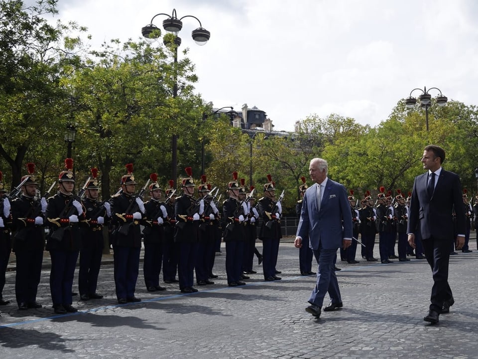 Charles und Macron schreiten eine Ehrengarde ab.