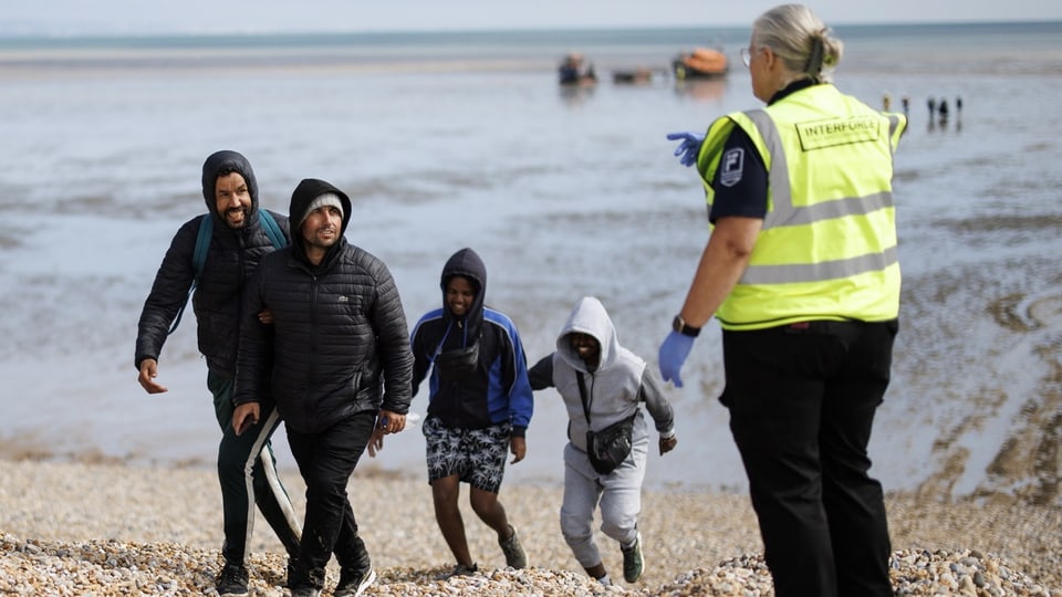 Flüchtlinge kommen an einem Strand an. 