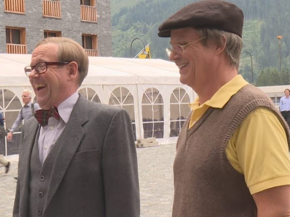 Zwei Männer stehen nebeneinander, beide lachen.