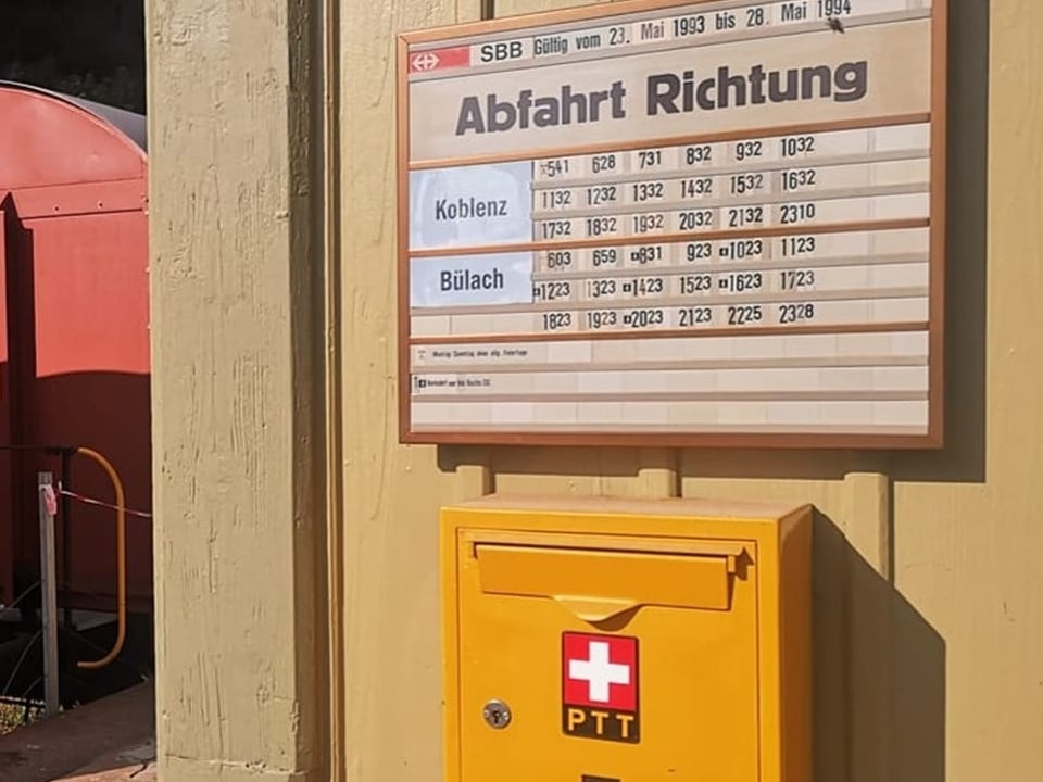 Blick auf alten Briefkasten und Fahrplananzeige.