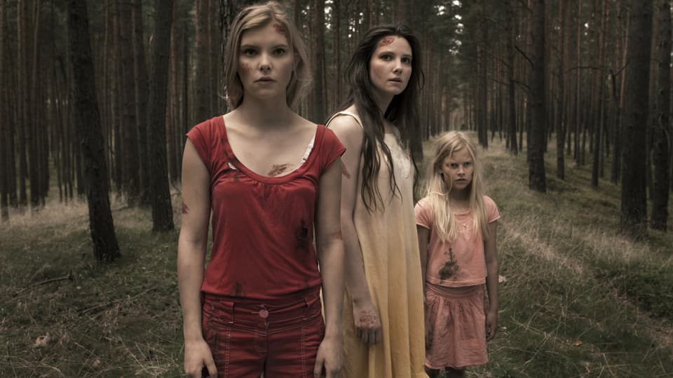 Drei Frauen stehen im Wald.