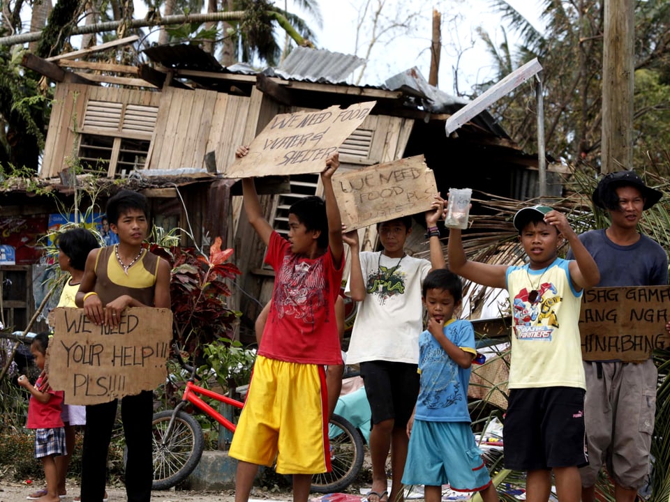Kinder stehen am Strassenrand mit Schildern: "Helft uns. Wir haben Hunger."