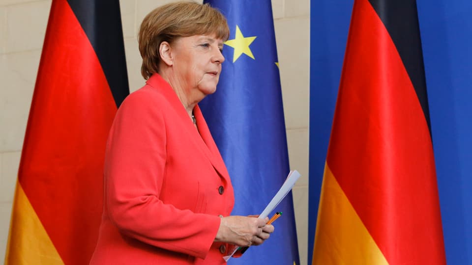 Angela Merkel vor Fahnen der BRD und der EU