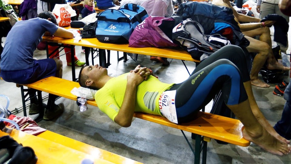 2 Männer erholen sich vom Marathon, sie liegen erschöpft auf einer Sitzbank