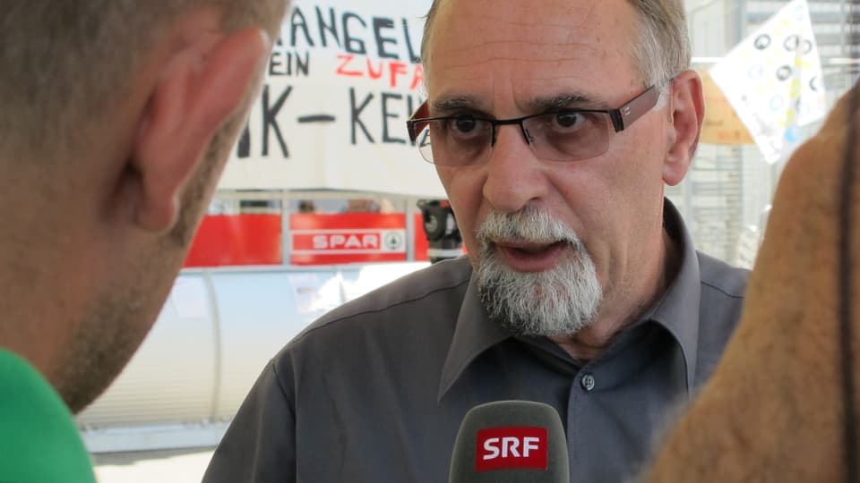 Emmenegger im Interview mit SRF, mit Brille und grauem Hemd.