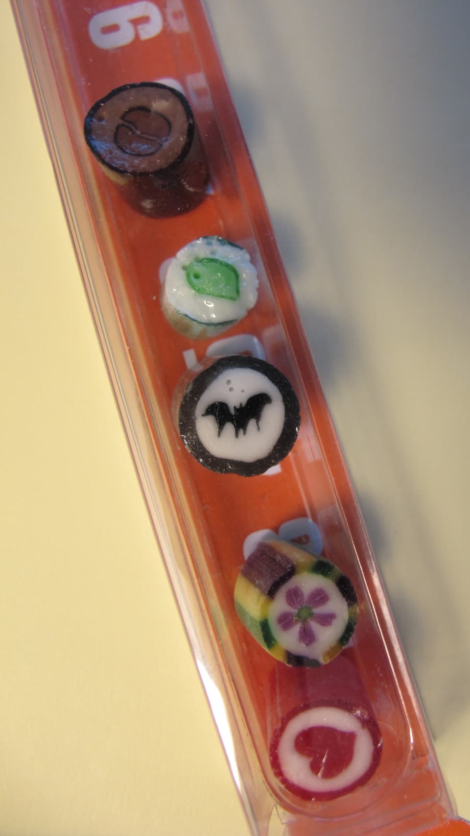 Fünf Bonbons mit Herz, Blume, Fledermaus, Blatt und Kaffee-Motiv.