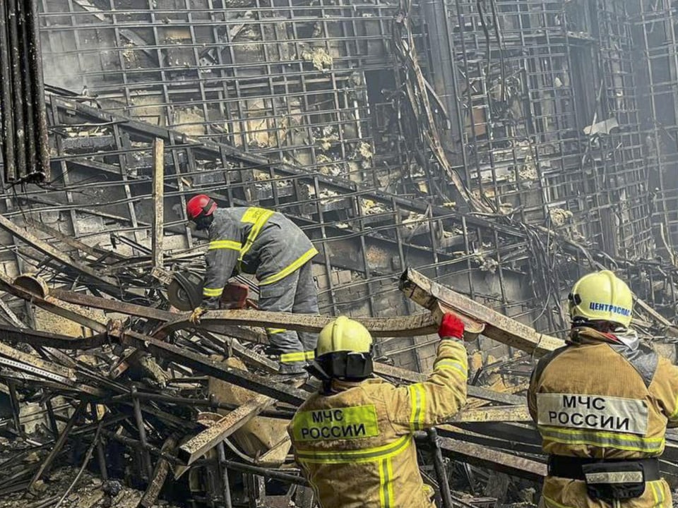 Feuerwehrleute tragen verbrannte Trümmerteile ab
