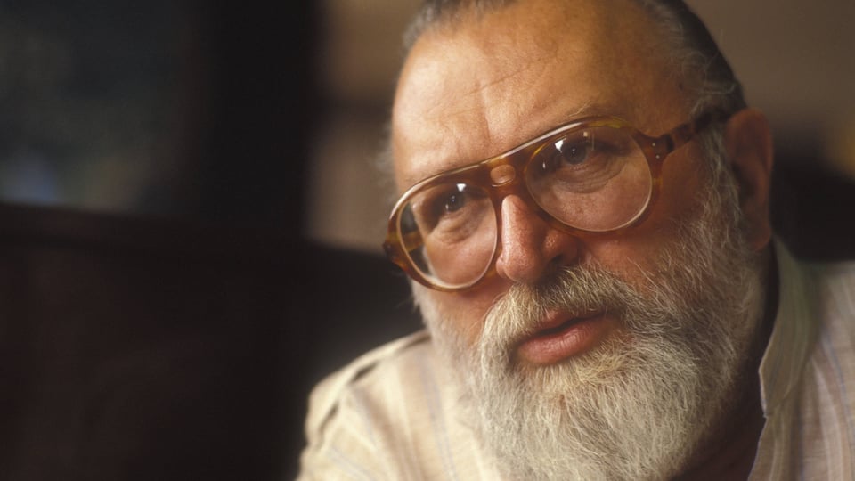 Porträt eines älteren Mannes mit Bart und Brille.