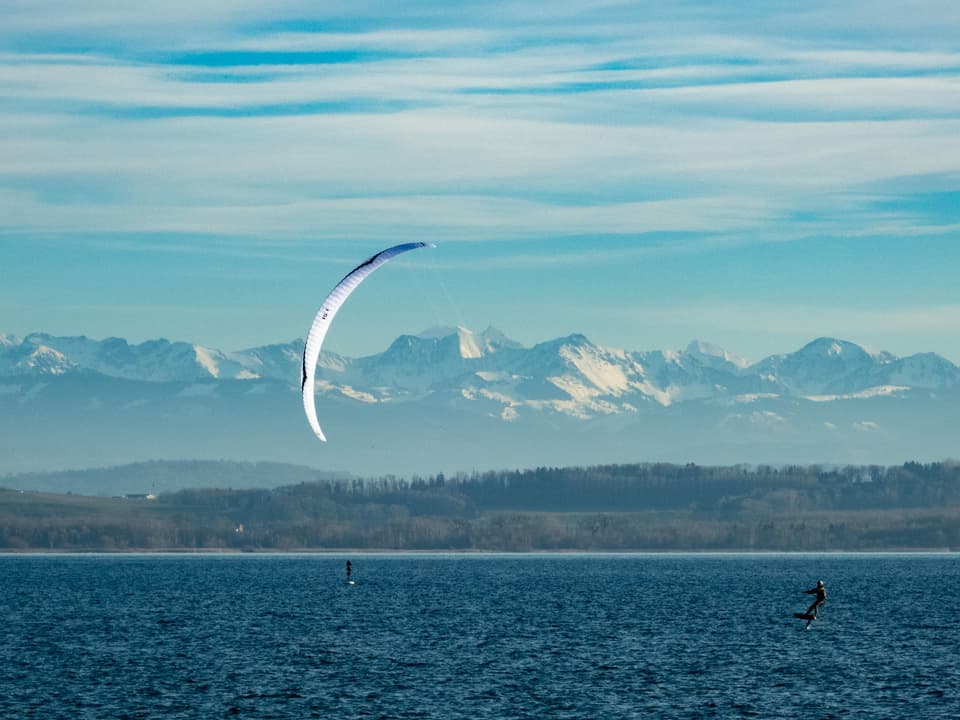 Ein Kitesurfer mit einem Mattenkite und einem Foil unterwegs auf einem See.