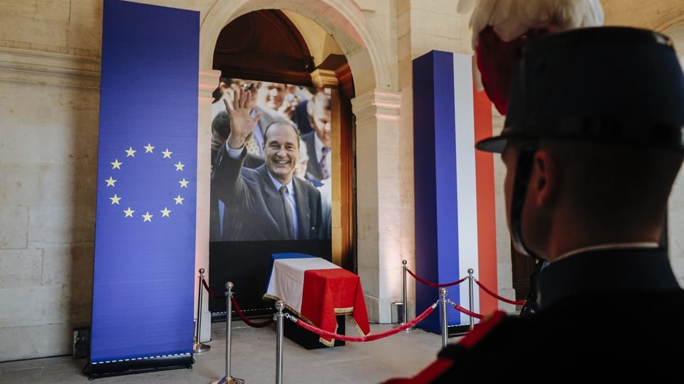 Sarg des Präsidenten in einer Nische. Darum herum die Fahne Frankreichs und der EU. Dahinter ein Fotos Chiracs.