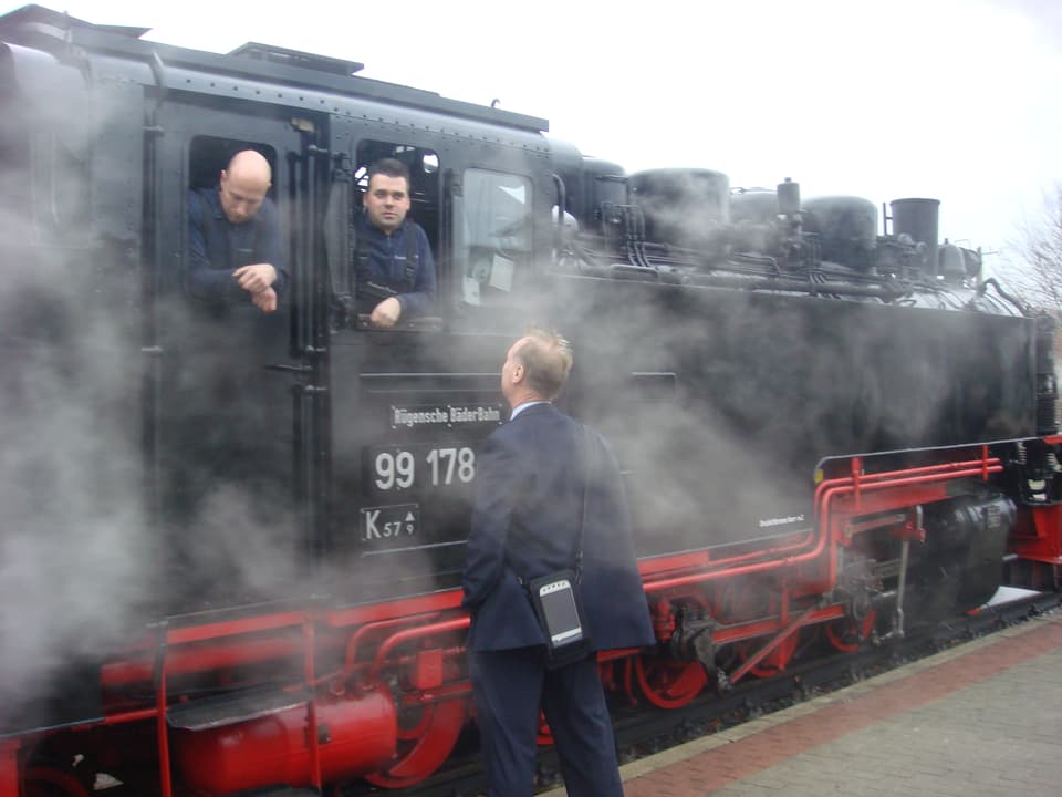 Schaffner und Lokführer diskutieren am Führerstand einer Dampflokomotive