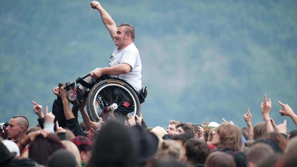 Ein junger Mann im Rollstuhl an einem Rockkonzert – auf Händen getragen von einer Menschenmasse.