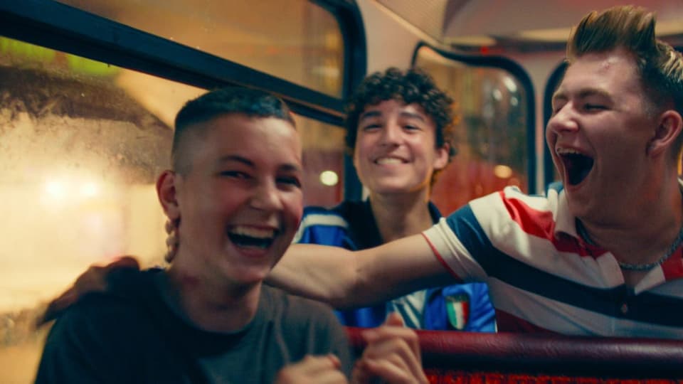 Drei Jugendliche lachen im Bus bei Nacht, 