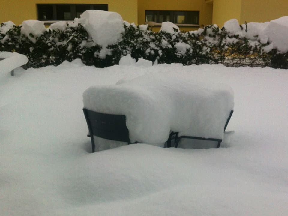 Schneemassen auf Gartenstühlen.