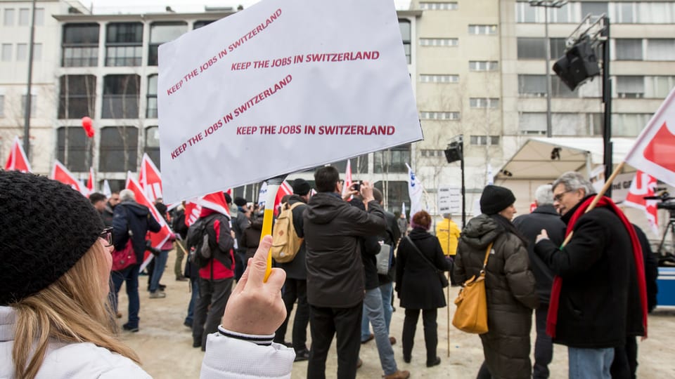 Demonstrantin hält Plakat in die Höhre "kee the Jobs in Switzerland"