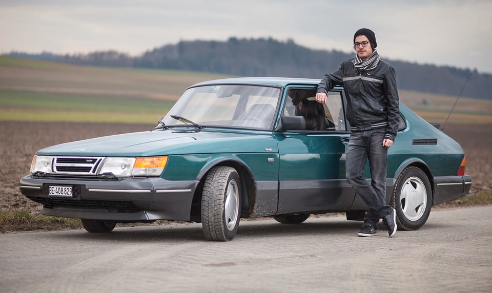 Ein Mann steht vor einem grünen Saab.