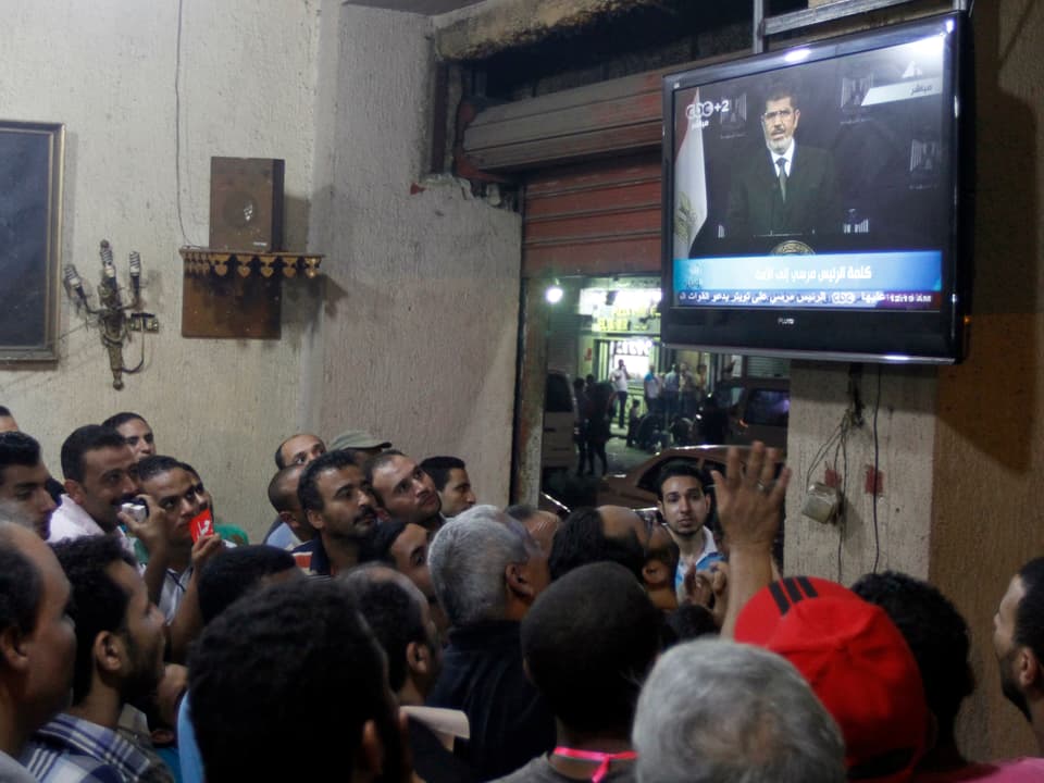 Männer in einem Café in Kairo, sie schauen eine Fernsehansprache von Mohamed Mursi. 