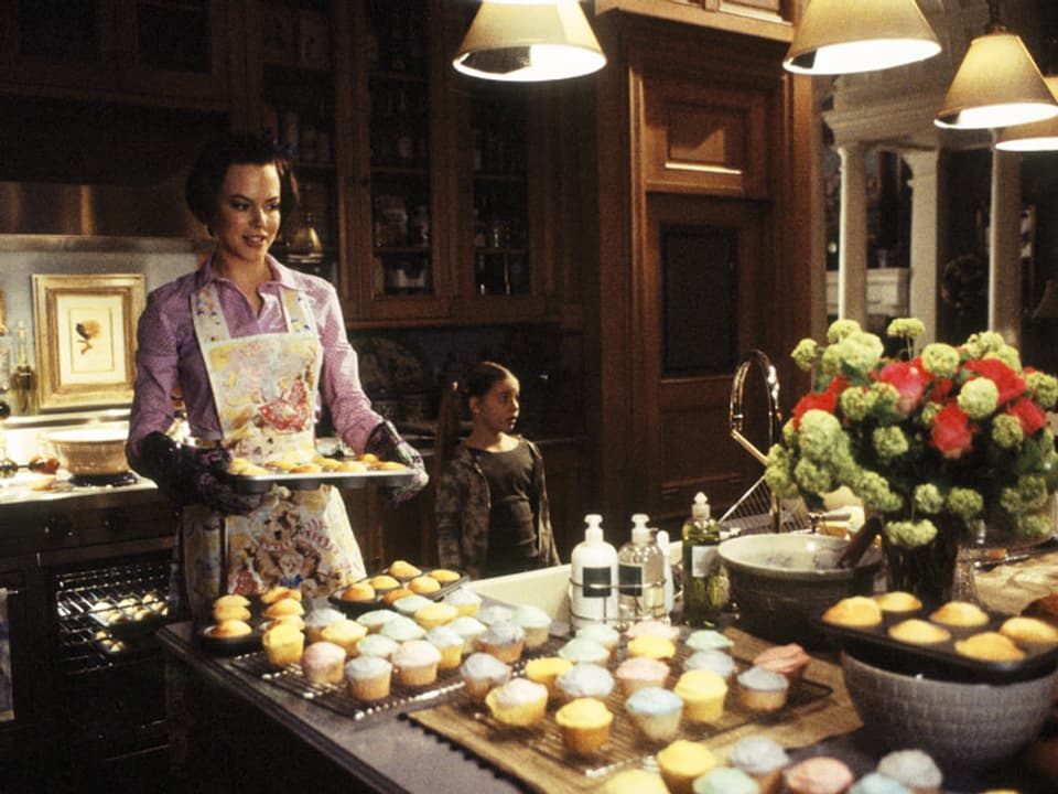 Nicole Kidman als Joanna Eberhard mit Kochschürze und einem Tablett voller Gebäck in der Hand.