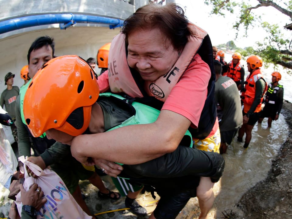 Ein Helfer bringt einen Anwohner der Stadt in der Bulacan-Provinz auf seinem Rücken in Sicherheit.