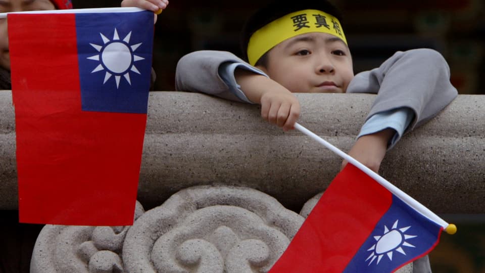 Ein Bub hält die Flagge von Taiwan in den Händen.