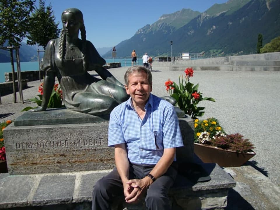 Ein Mann sitzt vor einem Denkmal.