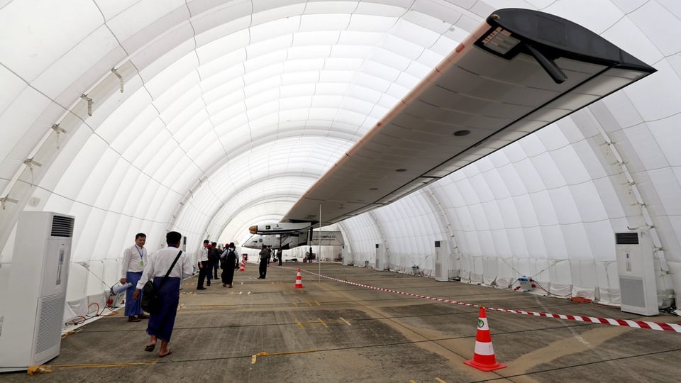 Ein weisses, langes Zelt als Hangar für das Solarflugzeug mit seinen langen Flügeln.