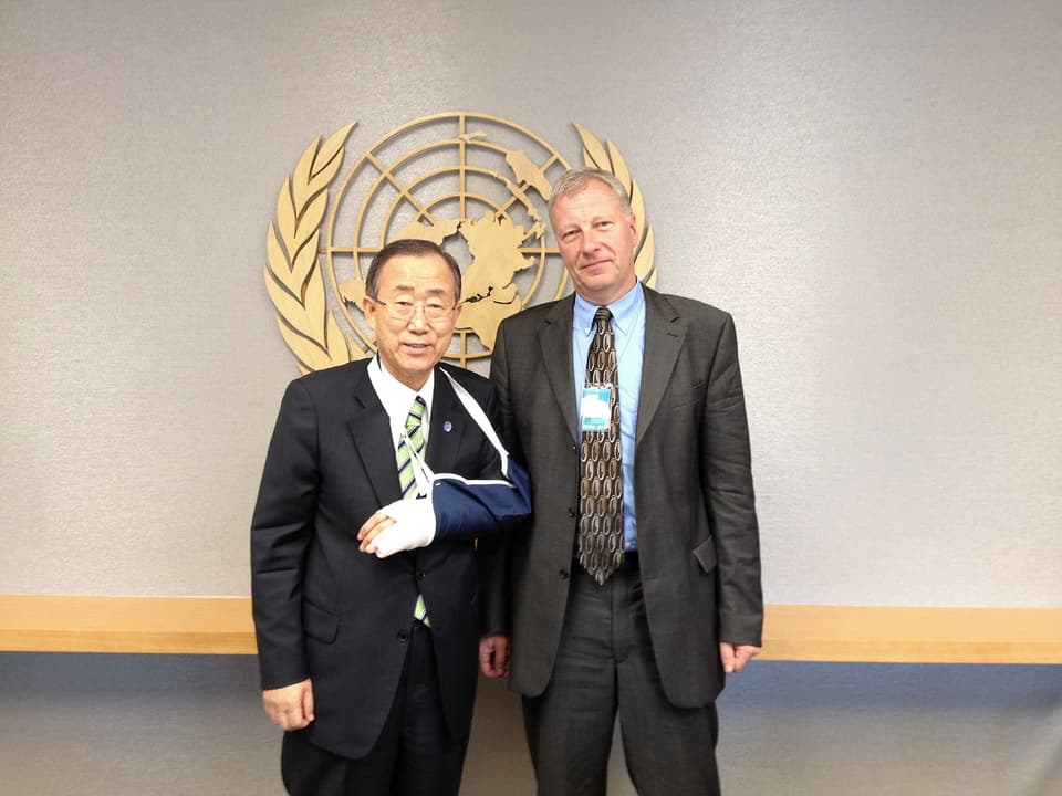 Fredy Gsteiger posiert mit Ban Ki-moon vor dem goldenen UNO-Symbol an der Wand.