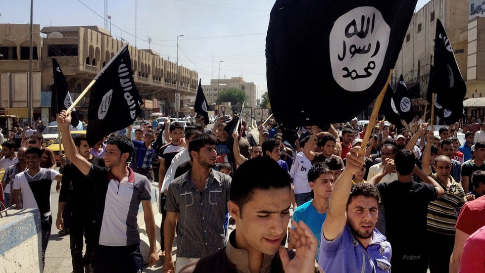 Sympathisanten schwenken schwarze islamistische Flaggen an einer Demonstation in Irak.