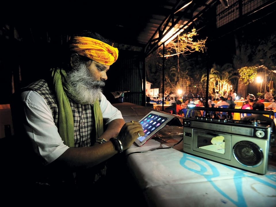 Inder sitzt vor einem Radiogerät und einem iPad.